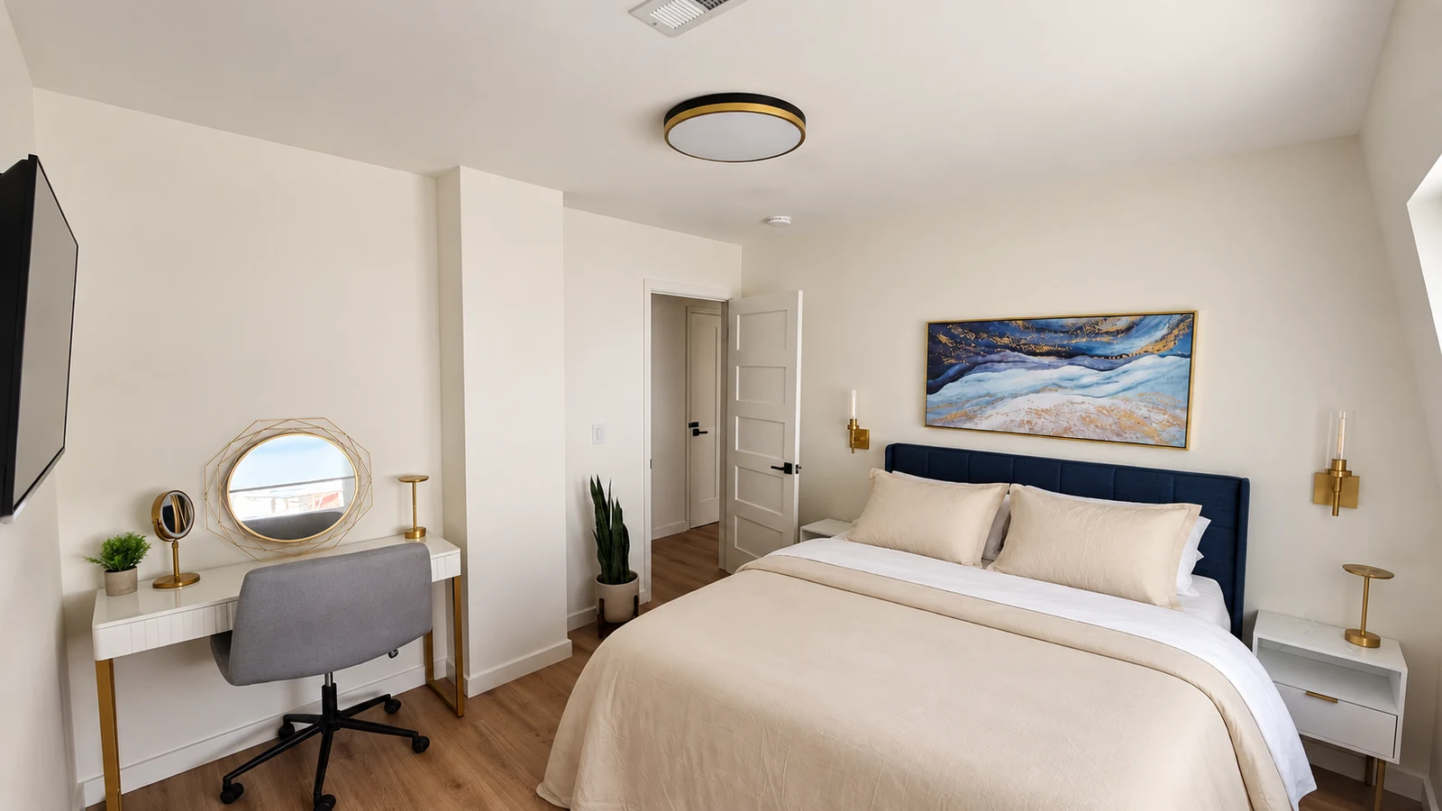 The Gatsby Room with vanity desk, gold sconces, and blue abstract art