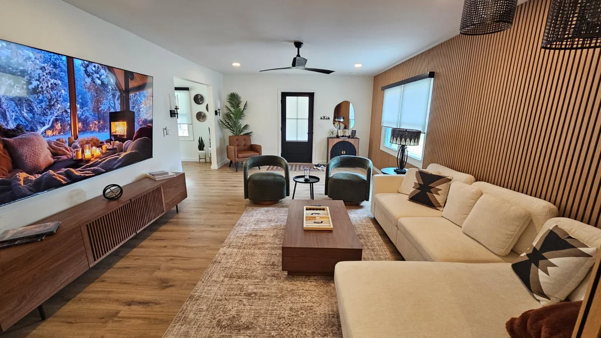 The real front living room at Mojo Manor, with cream sectional, green chairs and wood-slat wall